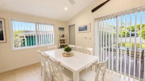 a dining room with a white table and chairs at Sandy Feet in Wooli