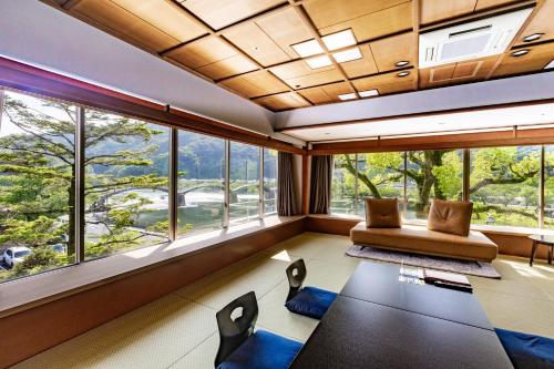 a living room with a table and chairs and windows at Iwakuni Kokusai Kanko Hotel in Iwakuni