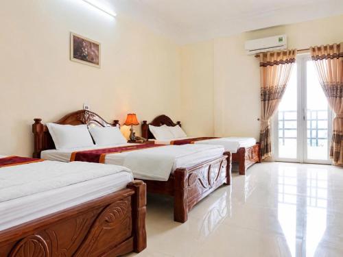 a hotel room with three beds and a window at LiLy Hotel Ninh Bình in Ninh Binh