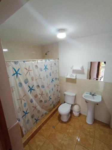 a bathroom with a toilet and a sink and a shower curtain at Hospedaje Hacienda Norabuena in Recuay