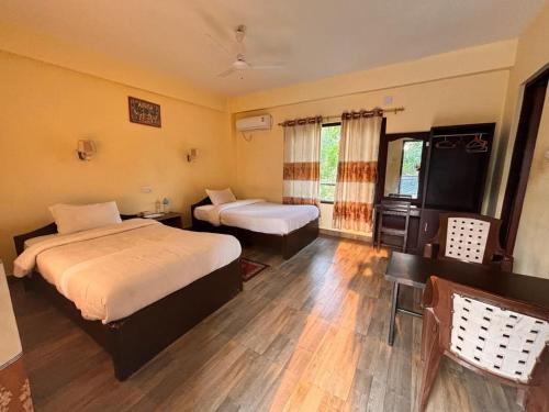 a hotel room with two beds and a table and chairs at silent park sauraha in Sauraha