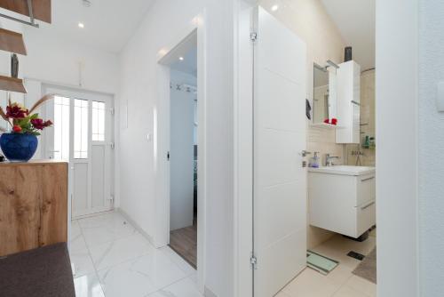 a white bathroom with a sink and a mirror at Monte Mare in Donji Seget