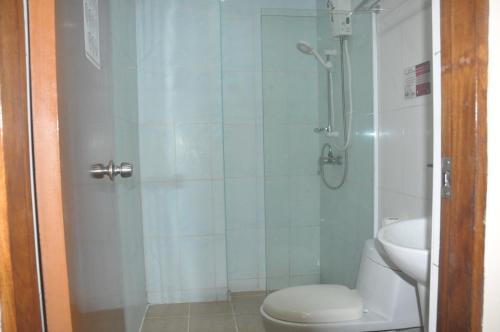 a bathroom with a shower with a toilet and a sink at A&A Plaza Hotel in Puerto Princesa City