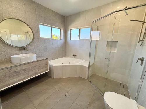 a bathroom with a tub and a sink and a mirror at Parkview Lodge - Bring your own linen. in South West Rocks
