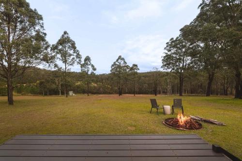two chairs sitting next to a fire in a field at Two-Ki by Tiny Away in Rainbow Flat