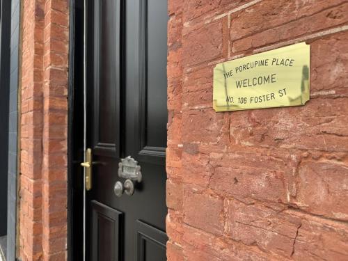 a sign on a brick wall next to a door at The Porcupine Place in Sale