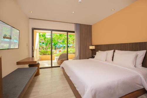 a bedroom with a large white bed and a balcony at Pamookkoo in Kata Beach