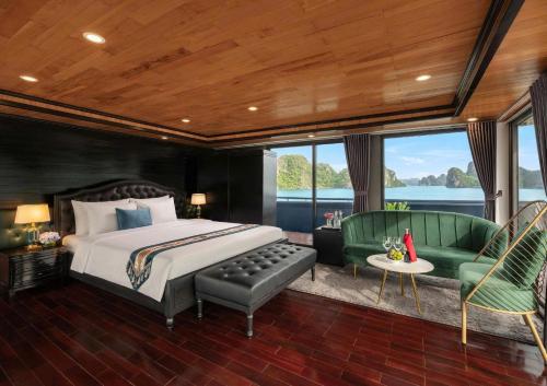 a bedroom with a bed and two green chairs at Aqua Elegance Cruise - Halong Bay by AHG in Ha Long