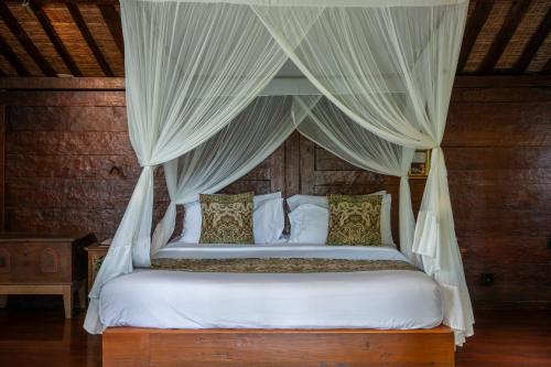 a bedroom with a canopy bed with white sheets and pillows at Aryaswara Villa Ubud in Ubud