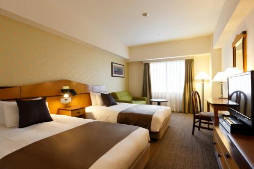 a hotel room with two beds and a television at Hotel Resol Gifu in Gifu