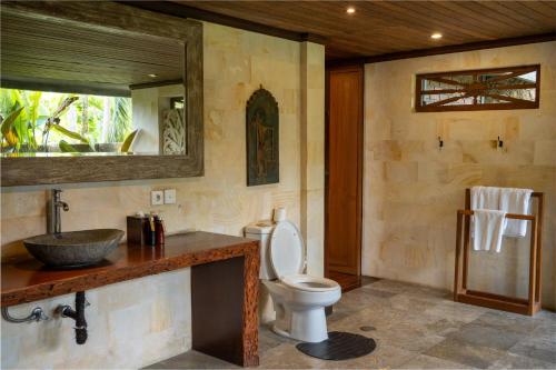 a bathroom with a toilet and a sink and a mirror at Aryaswara Villa Ubud in Ubud