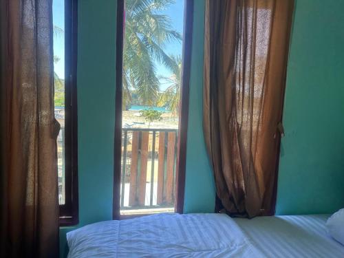 a bedroom with a bed and two large windows at Novena bungalow Oeseli in Pulau Helihana
