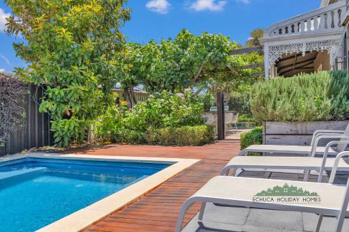 a backyard with a swimming pool with chairs and a gazebo at Central Charm in Echuca