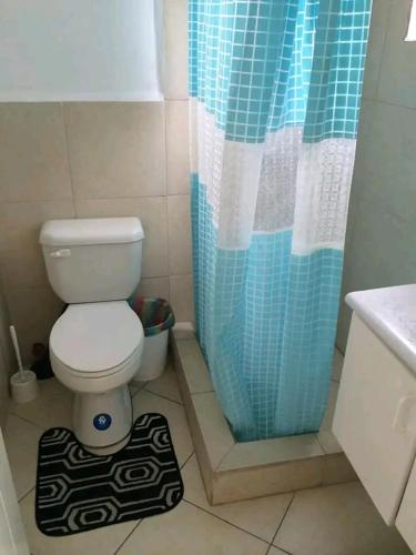 a bathroom with a toilet and a blue shower curtain at Exclusivo Departamento playa in Same