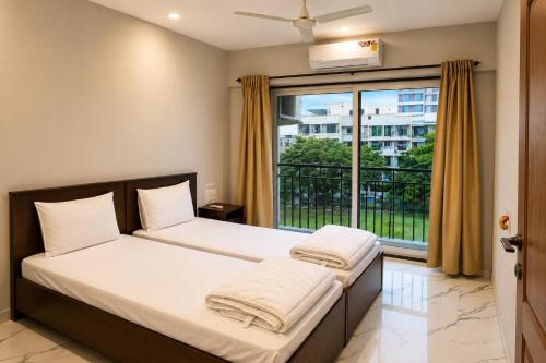 a bedroom with two beds and a large window at ASPA Apartments in Navi Mumbai