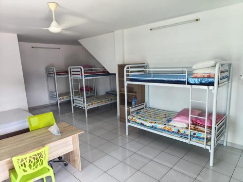 a room with three bunk beds and a wooden table at Sun Flower Guest House 17mins to Ipoh Town in Ipoh