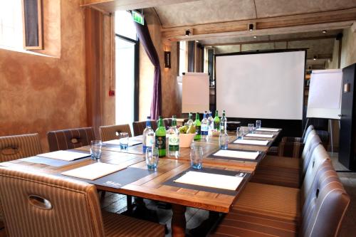 a long wooden table in a room with bottles of wine at Malmaison Oxford in Oxford