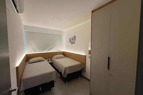 a small room with two beds and a closet at Flat 2/4 - Prestige 204 - Praia do Francês in Marechal Deodoro