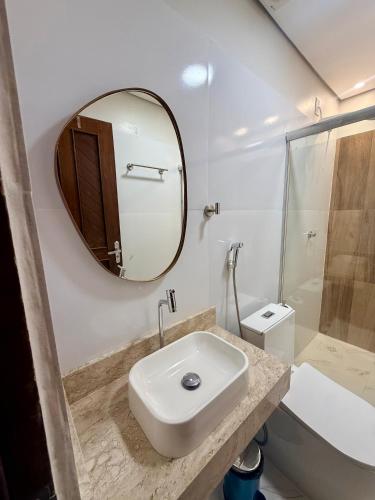 a white bathroom with a sink and a mirror at Pousada Santos in Parintins