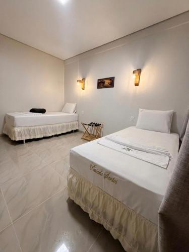 two beds in a room with white walls at Pousada Santos in Parintins