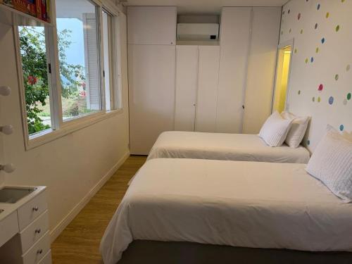 two beds in a room with two windows at Sítio Paradouro in Novo Hamburgo