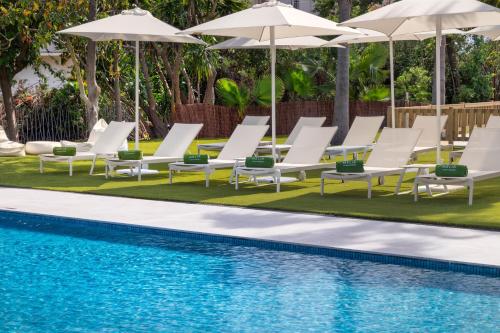 a group of lounge chairs and umbrellas next to a swimming pool at Meliá Lloret de Mar in Lloret de Mar