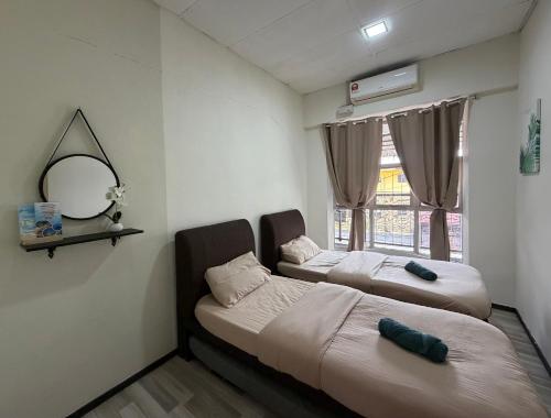 two beds in a room with a mirror and a window at Zero Gravity Homestay 零重力民宿 in Semporna