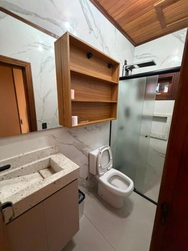 a bathroom with a toilet and a glass shower at Chalé Rossa in Xangri-lá