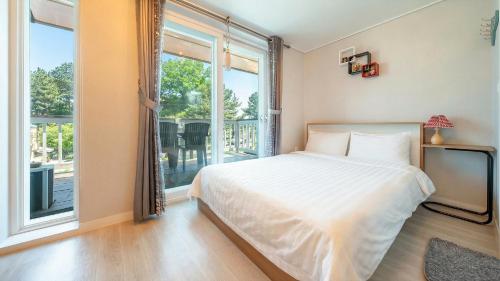 a bedroom with a bed and a large window at Goseong Araenmaru Pension in Goseong