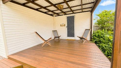 two chairs on a wooden deck with a pergola at Teke Cottage in Wooli