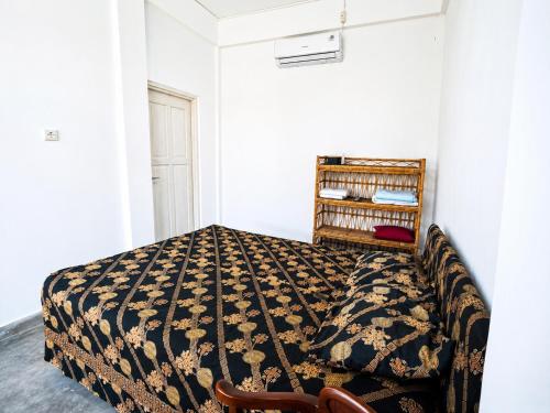 a bedroom with a bed with a blanket on it at Kaliele House in Domine Eduard Osok Airport