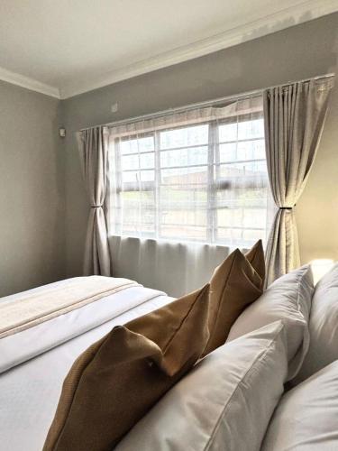 a bedroom with a bed with a window with curtains at Caysa Villa in Gaborone