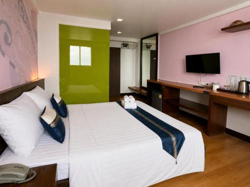 a bedroom with a large bed with a desk and a television at Happyland Mansion in Bangkok