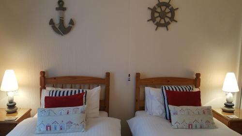 a bedroom with two beds and a clock on the wall at Tregonwell House - Guest House in Minehead