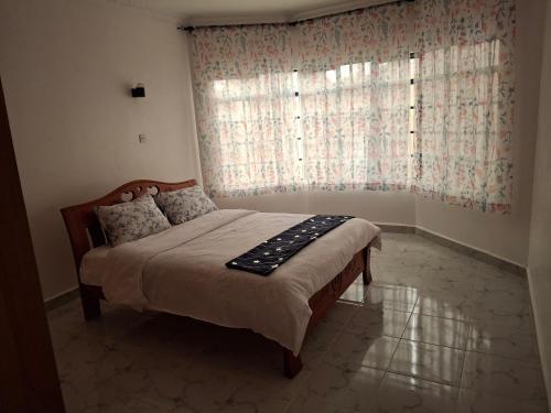 a bedroom with a bed and a large window at BlessRoyal Home in Kitengela 