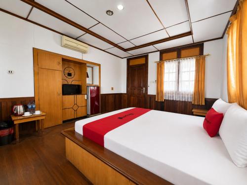 a bedroom with a large white bed with red pillows at RedDoorz at Derawan Beach Cottage in Derawan Islands
