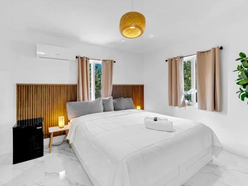 a white bedroom with a large white bed and windows at Casa Playa Coastal Comfort 10 Min From Beach in Hallandale Beach