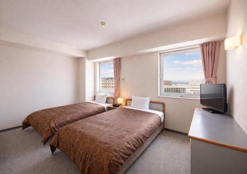 a hotel room with a bed and a flat screen tv at Hotel Airport Komatsu in Komatsu