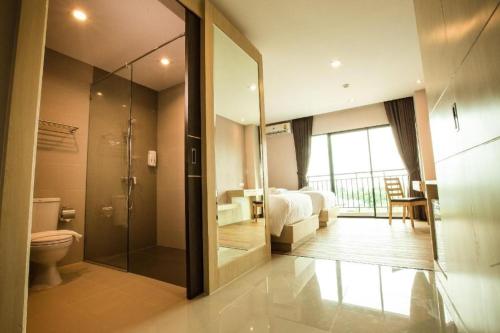 a bedroom with a bed and a bathroom with a shower at L Hotel in Ban Si Than