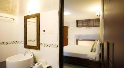 a bathroom with a sink and a mirror and a bed at At home boutique in Ban Long