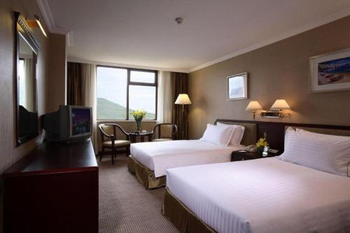 a hotel room with two beds and a television at Teda Dalian in Dalian
