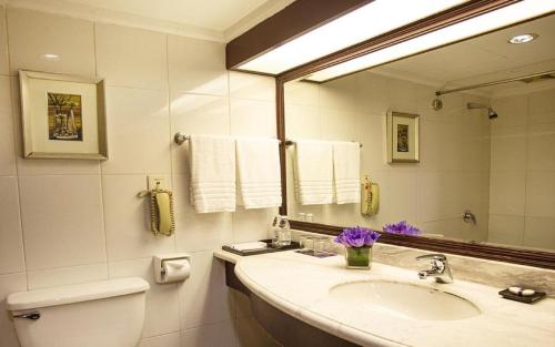 a bathroom with a sink and a toilet and a mirror at Teda Dalian in Dalian