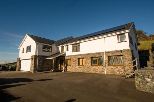 een groot wit huis met een parkeerplaats bij Y Grange in Llanfihangel-y-creuddyn