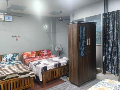 a bedroom with two beds and a cabinet at Maha Periyava Kuteeram 10 Adults Budget Stay in Kumbakonam