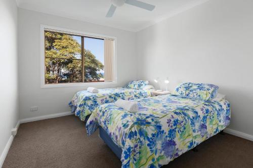 two beds in a room with a window at Ocean Retreat in Nambucca Heads