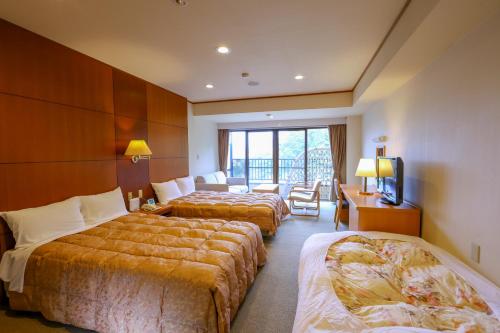 a hotel room with three beds and a television at Yugawara Chiyodasou in Yugawara