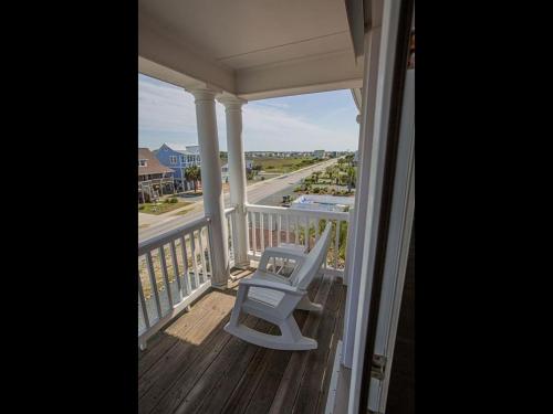 a white chair on a porch with a view of the ocean at Ohana Tides Home in Holden Beach