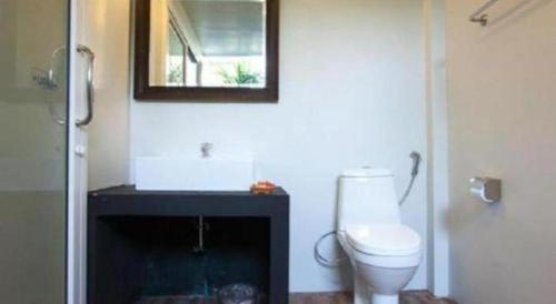 a bathroom with a toilet and a mirror on the wall at Baan Kula Mahasarakam in Ban Nong Chik