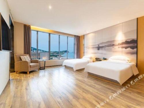 a hotel room with two beds and a television at Qingdao Elegance Hotel in Qingdao