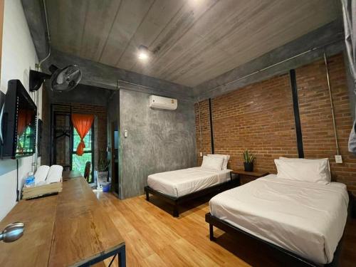 a bedroom with two beds and a brick wall at palmhouse in Mae Hong Son